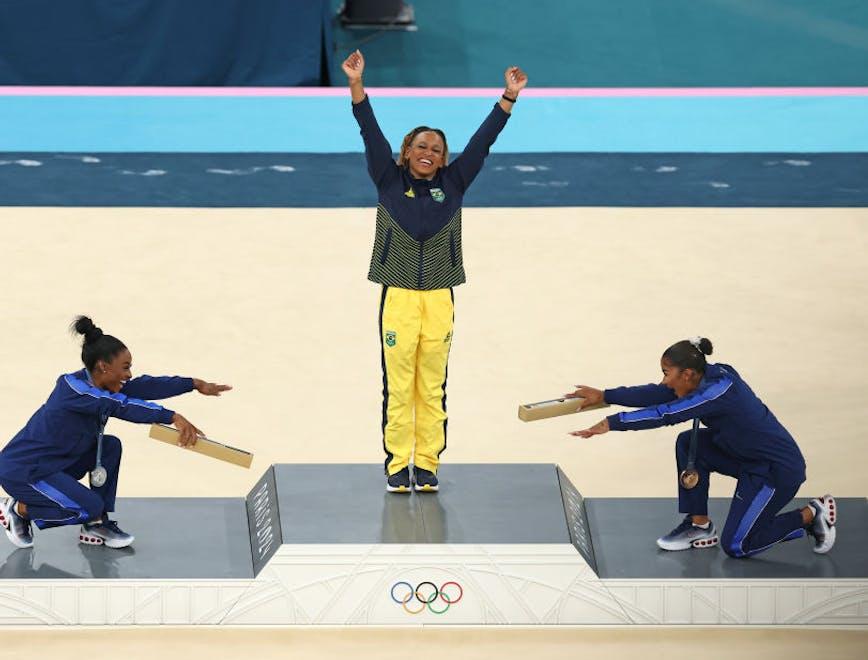 Rebeca Andrade no pódio reverenciada por Simone Biles e Jordan Chiles (Foto: Getty Images)