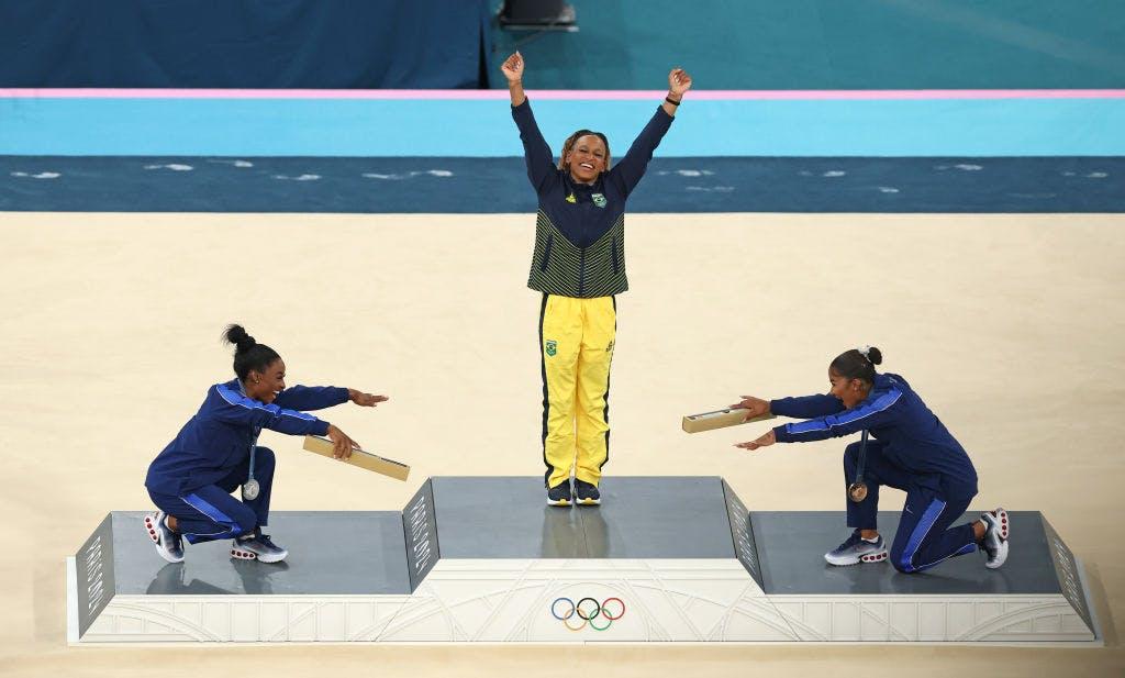 Rebeca Andrade no pódio reverenciada por Simone Biles e Jordan Chiles (Foto: Getty Images)